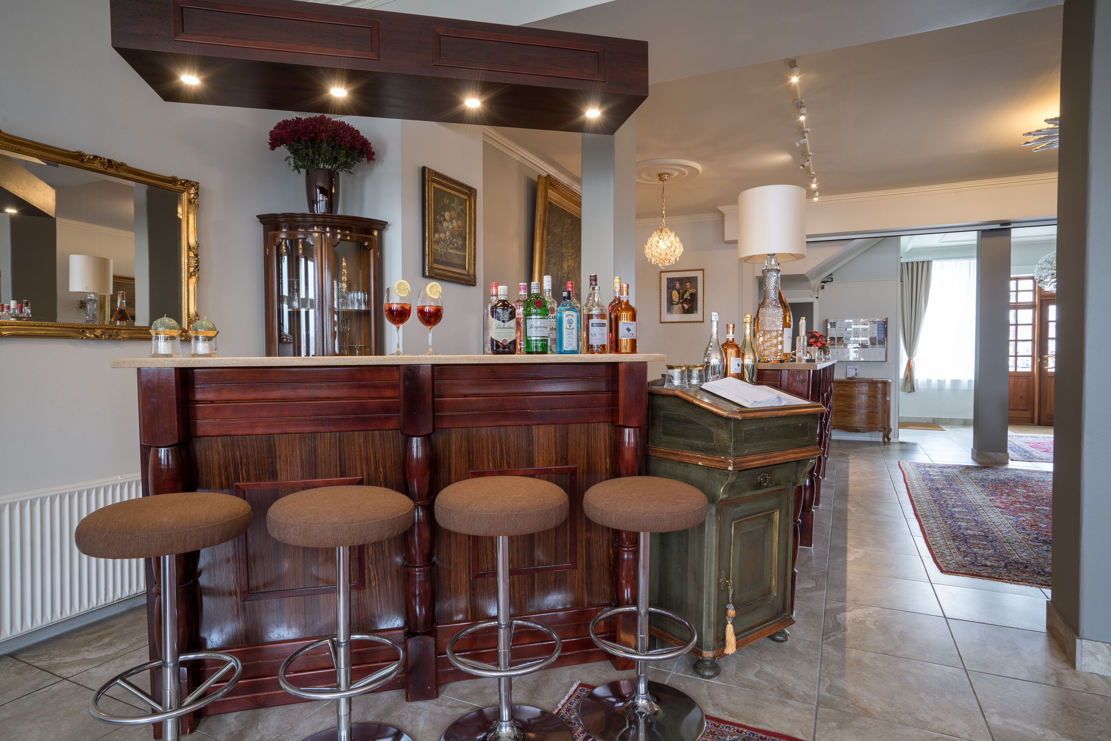 A bar area with stools, a mirror, and various bottles.