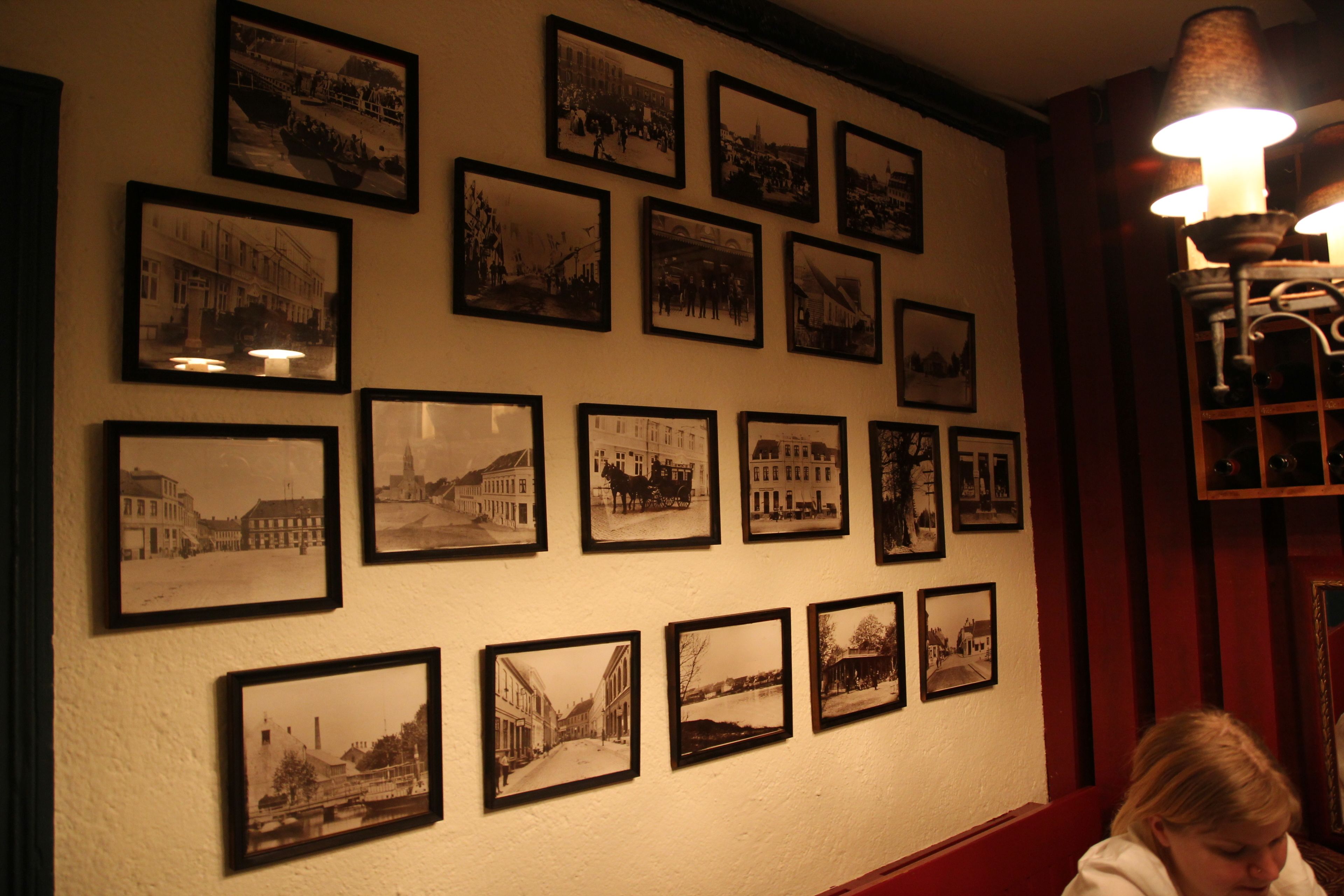 A wall with multiple black and white photographs of historical buildings and streets.