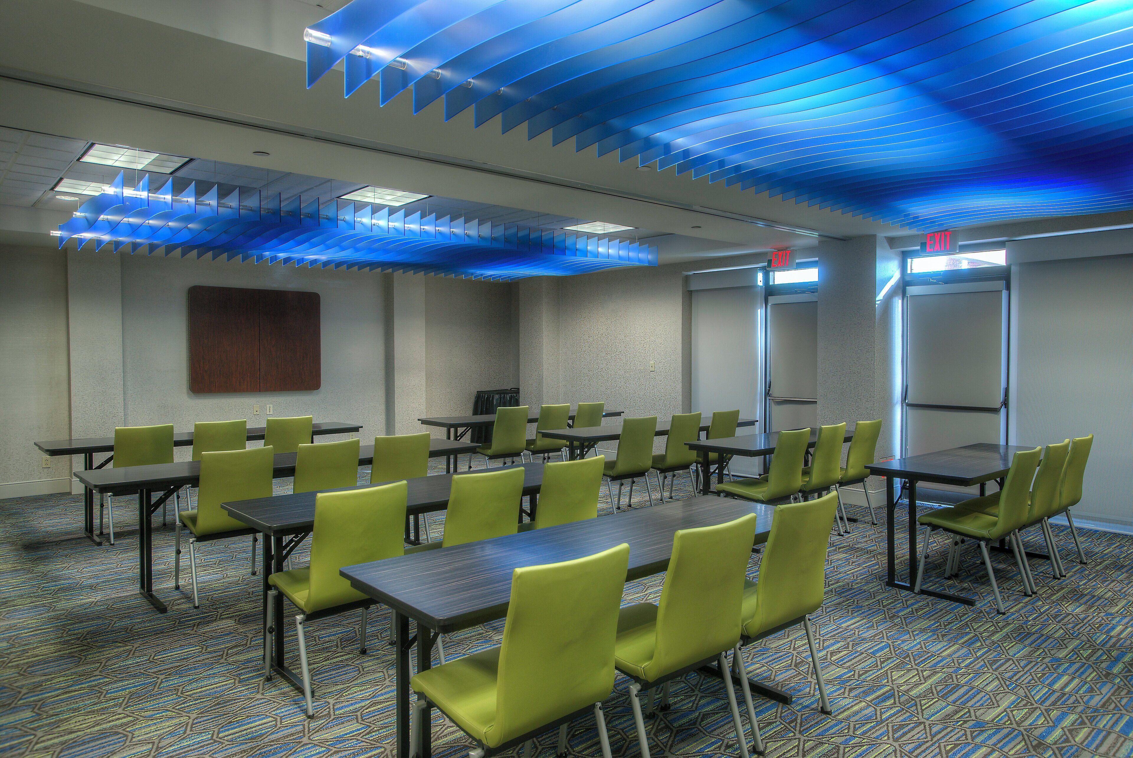 A conference room with tables and chairs, a patterned carpet, and a blue ceiling design.