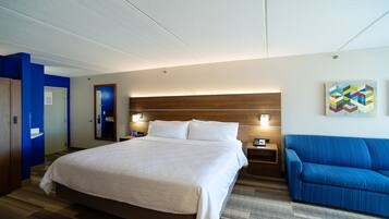 A hotel room with a large bed, bedside tables, a blue armchair, and a wooden headboard.