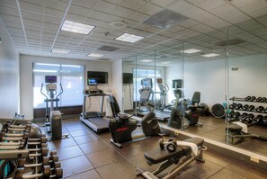 A gym with various exercise equipment including treadmills, stationary bikes, and dumbbells.