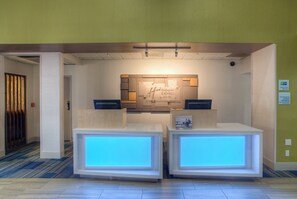 A reception area with a modern design, featuring a reception desk, a digital display, and a sign for Holiday Inn Express & Suites. - Holiday Inn Express & Suites Tempe by IHG (Tempe)