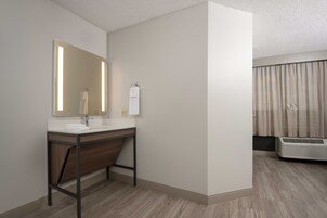 A modern bathroom with a wooden vanity, a large mirror, and a built-in air conditioning unit.