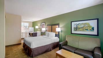 Une chambre d’hôtel avec un lit, un bureau, une chaise, un canapé et un tableau au mur.