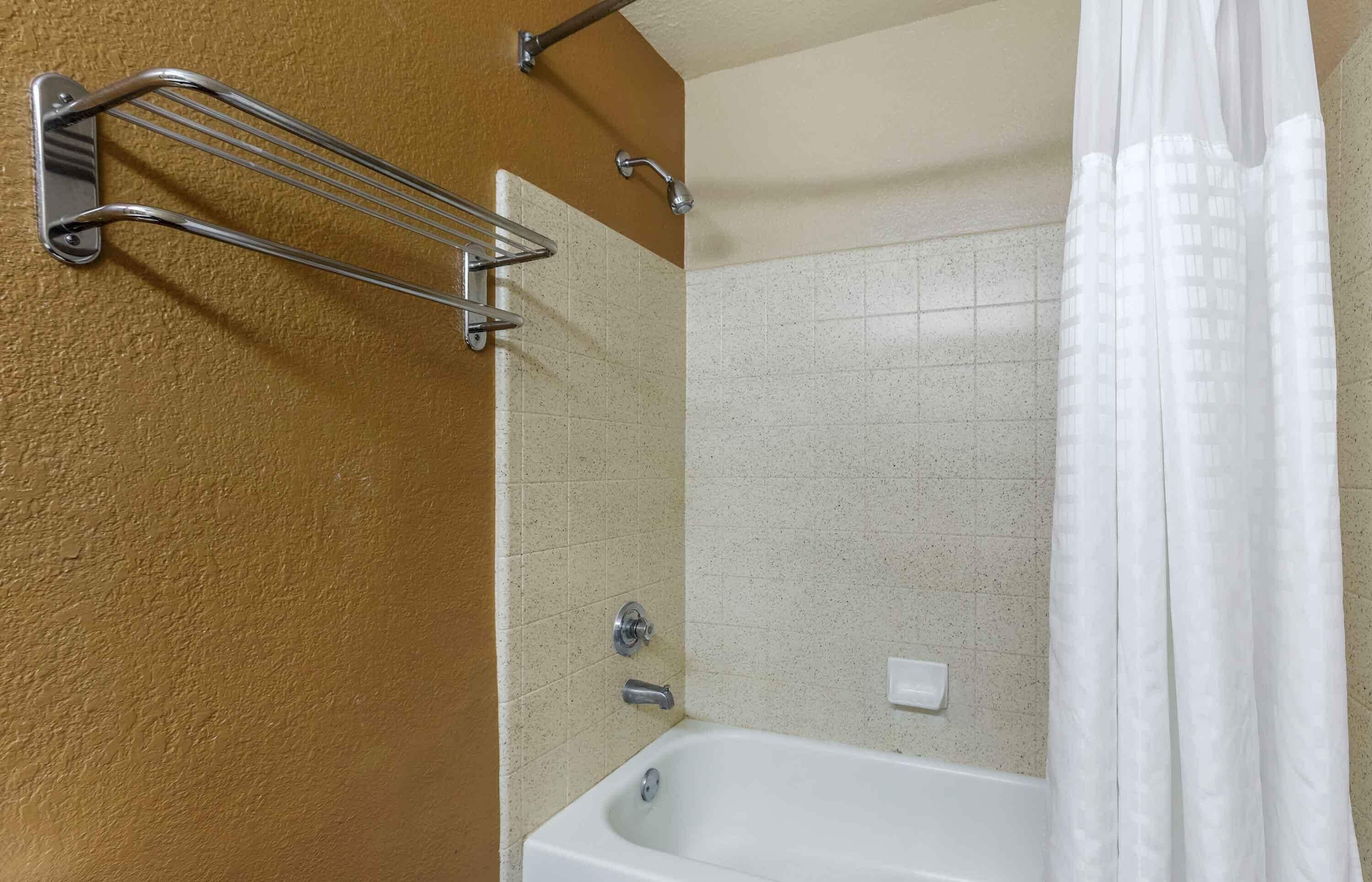 A bathroom with a bathtub, a shower curtain, and a towel rack.