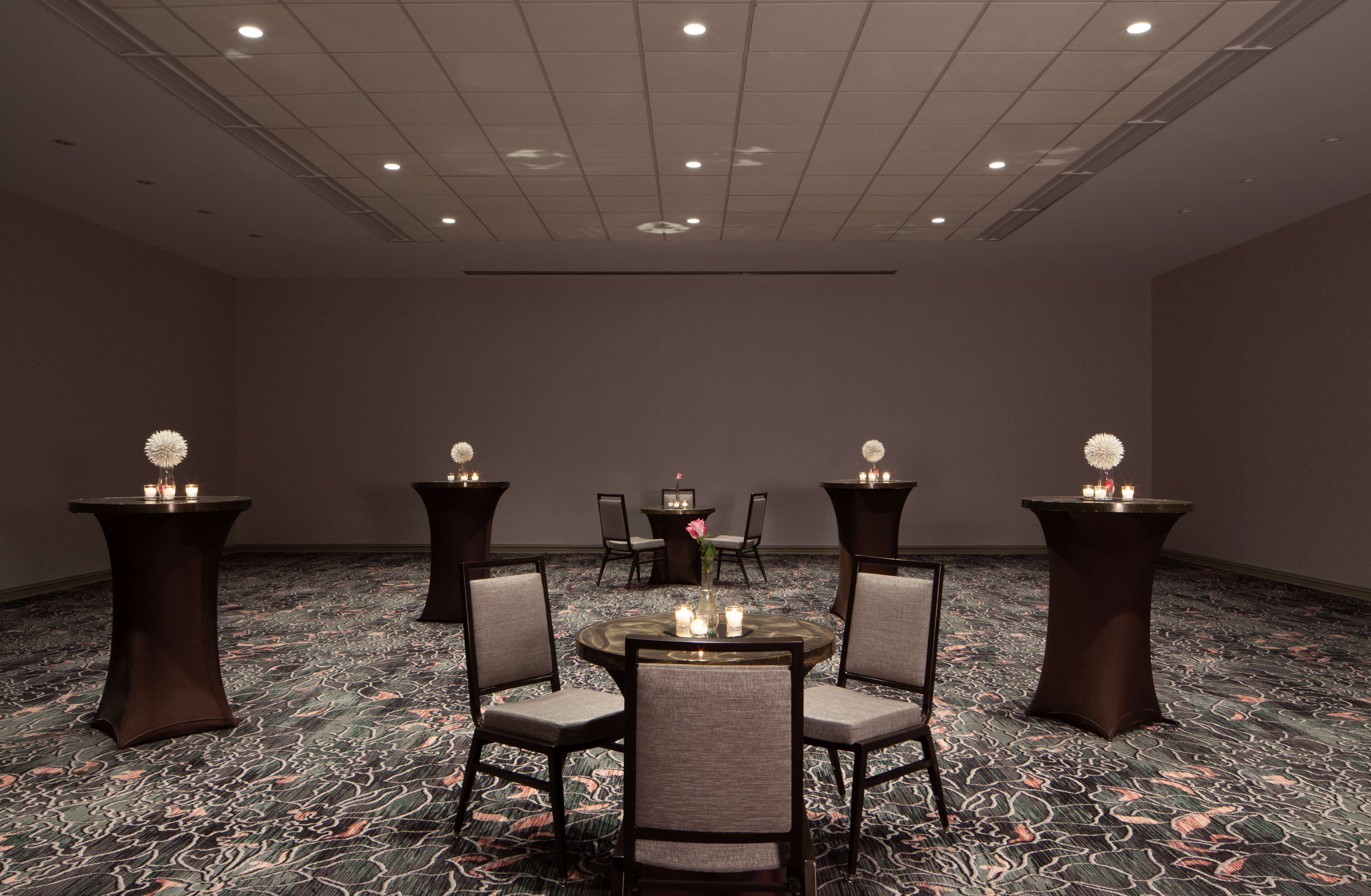 A conference room with a round table, four chairs, and three small tables with candles.
