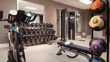 A gym with various equipment including dumbbells, a bench, and exercise balls.