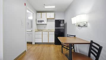 A compact kitchen with white cabinets, a microwave, and a black refrigerator.