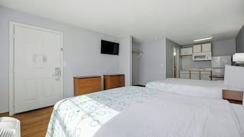 A hotel room with two beds, a wardrobe, a television, and a kitchenette.