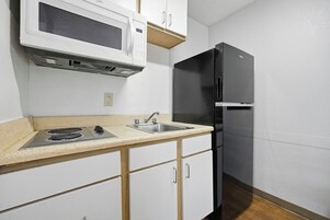A kitchen with a microwave, stove, sink, and black refrigerator.