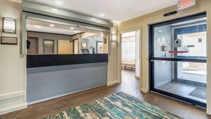 A reception area with a counter, a glass door entrance, and a visible exit sign. - Extended Stay America Select Suites Chicago Naperville East (Naperville)