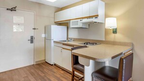 A compact kitchen with a refrigerator, microwave, and a small dining area with two chairs. - Extended Stay America Select Suites Chicago Naperville East (Naperville)