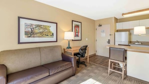 A hotel room with a sofa, desk, chair, and kitchenette. - Extended Stay America Select Suites Chicago Naperville East (Naperville)