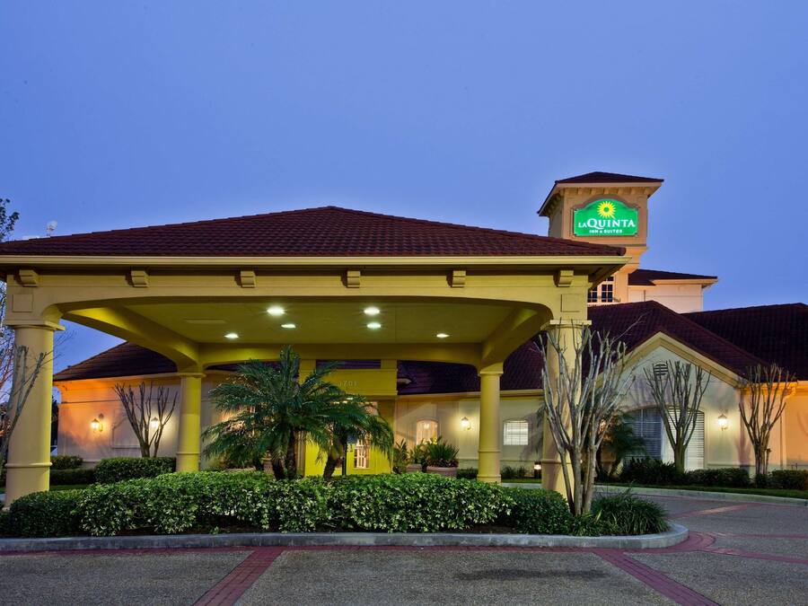 Entrada de hotel com área coberta, palmeiras e placa da La Quinta.
