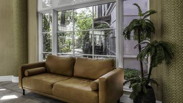 A room with a large window, a brown leather sofa, and a potted plant.