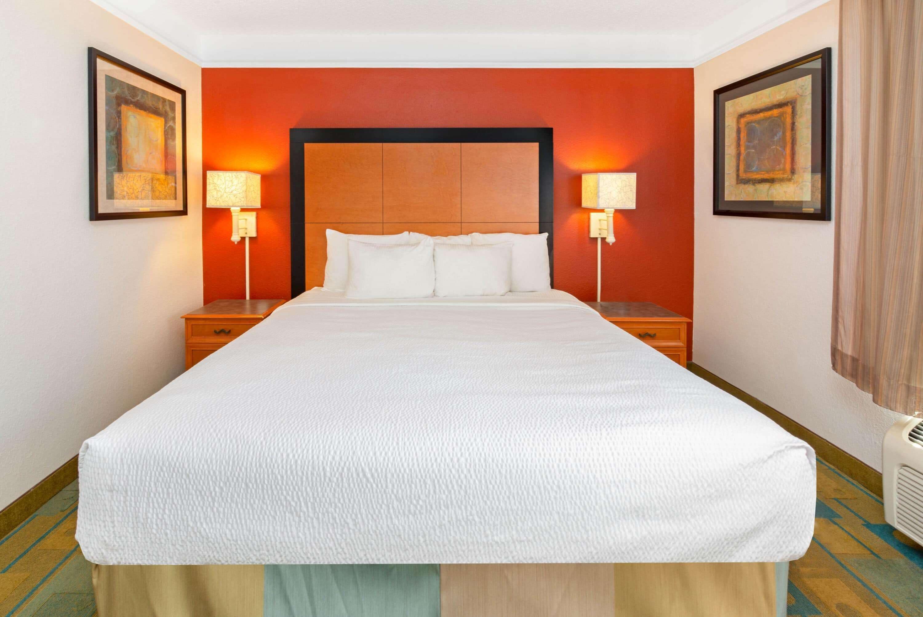 Una habitación de hotel con una cama grande, dos mesitas de noche y dos lámparas de pared.
