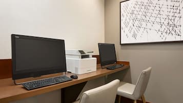 A workspace with two monitors, a printer, and a chair.