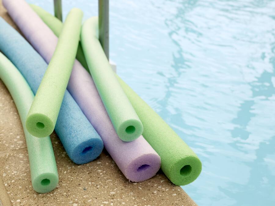 Een zwembadgedeelte met verschillende foamrollers in pastelkleuren.