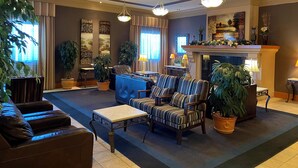 Un salón amplio con chimenea, sillones a rayas, una mesa de centro y varias plantas en macetas.