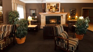 Una sala de estar acogedora con chimenea, sillones a rayas y plantas en macetas.