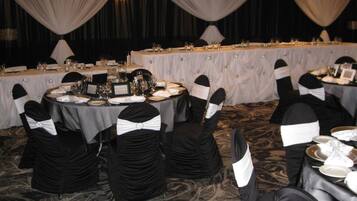 A banquet hall with round tables set for a formal event, each with place settings and glassware.
