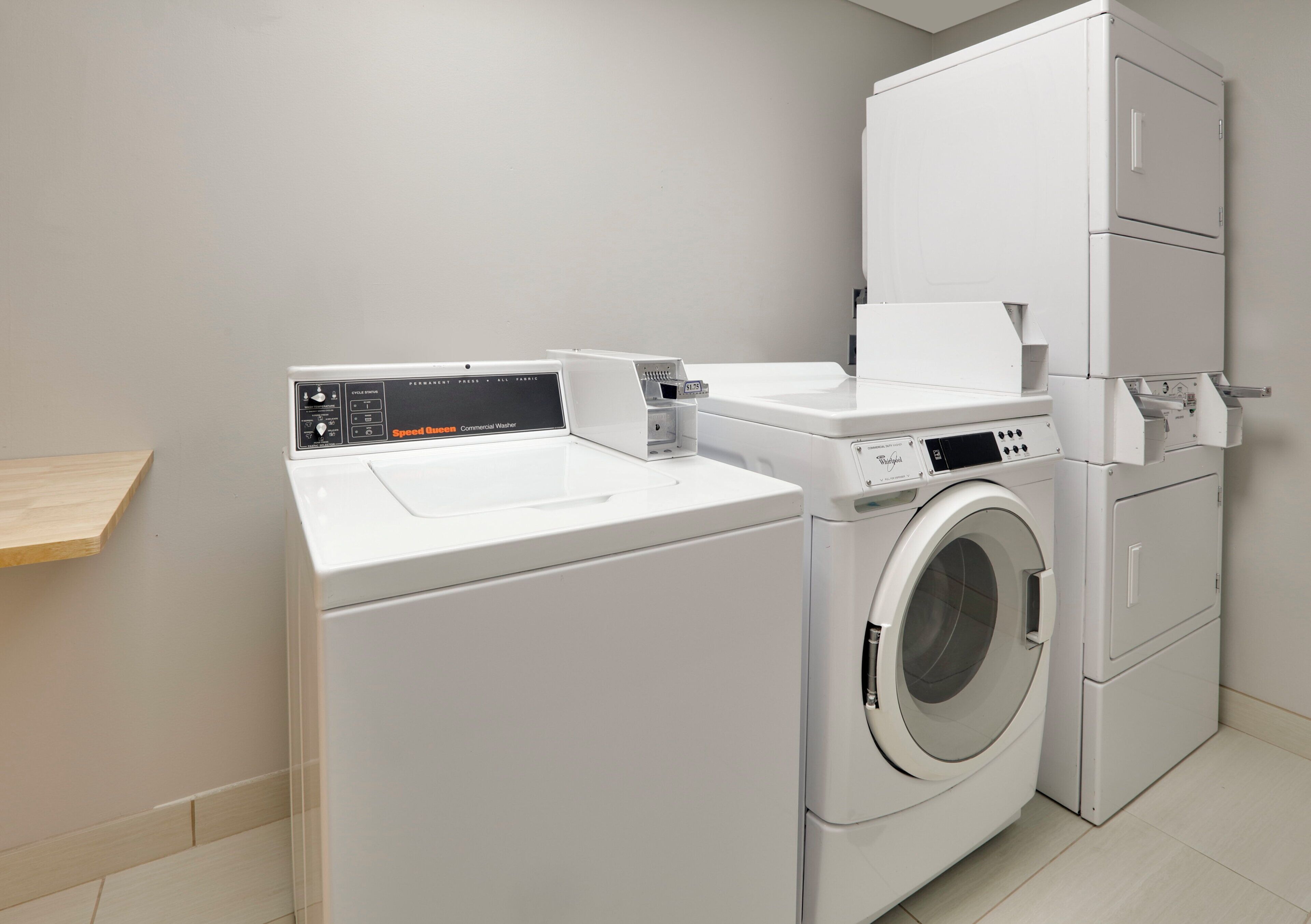 A compact, modern laundry room with a front-loading washing machine and a stacked dryer.