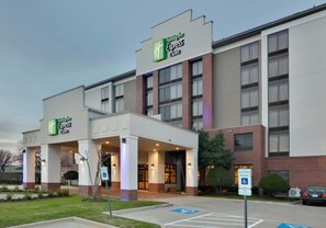 A Holiday Inn Express building with a brick facade, large windows, and a covered entrance area. - Holiday Inn Express & Suites Irving Conv Ctr - Las Colinas by IHG (Irving)