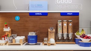 A breakfast bar with cereal and fruit options, a kettle, and condiments. - Holiday Inn Express & Suites Irving Conv Ctr - Las Colinas by IHG (Irving)