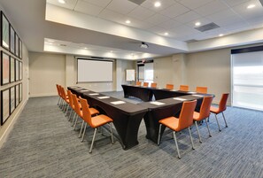 A conference room with a long table, orange chairs, a projector, a whiteboard, and framed pictures on the wall. - Holiday Inn Express & Suites Irving Conv Ctr - Las Colinas by IHG (Irving)