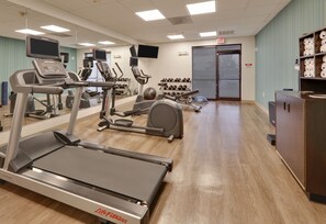 Un gimnasio con cintas de correr, elípticas y pesas sueltas.