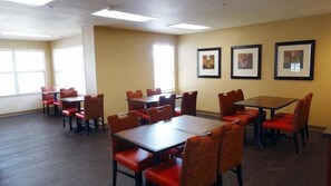 A conference room with multiple tables and chairs, framed artwork on the walls, and large windows allowing natural light. - Hawthorn Extended Stay by Wyndham Irving Las Colinas (Irving)