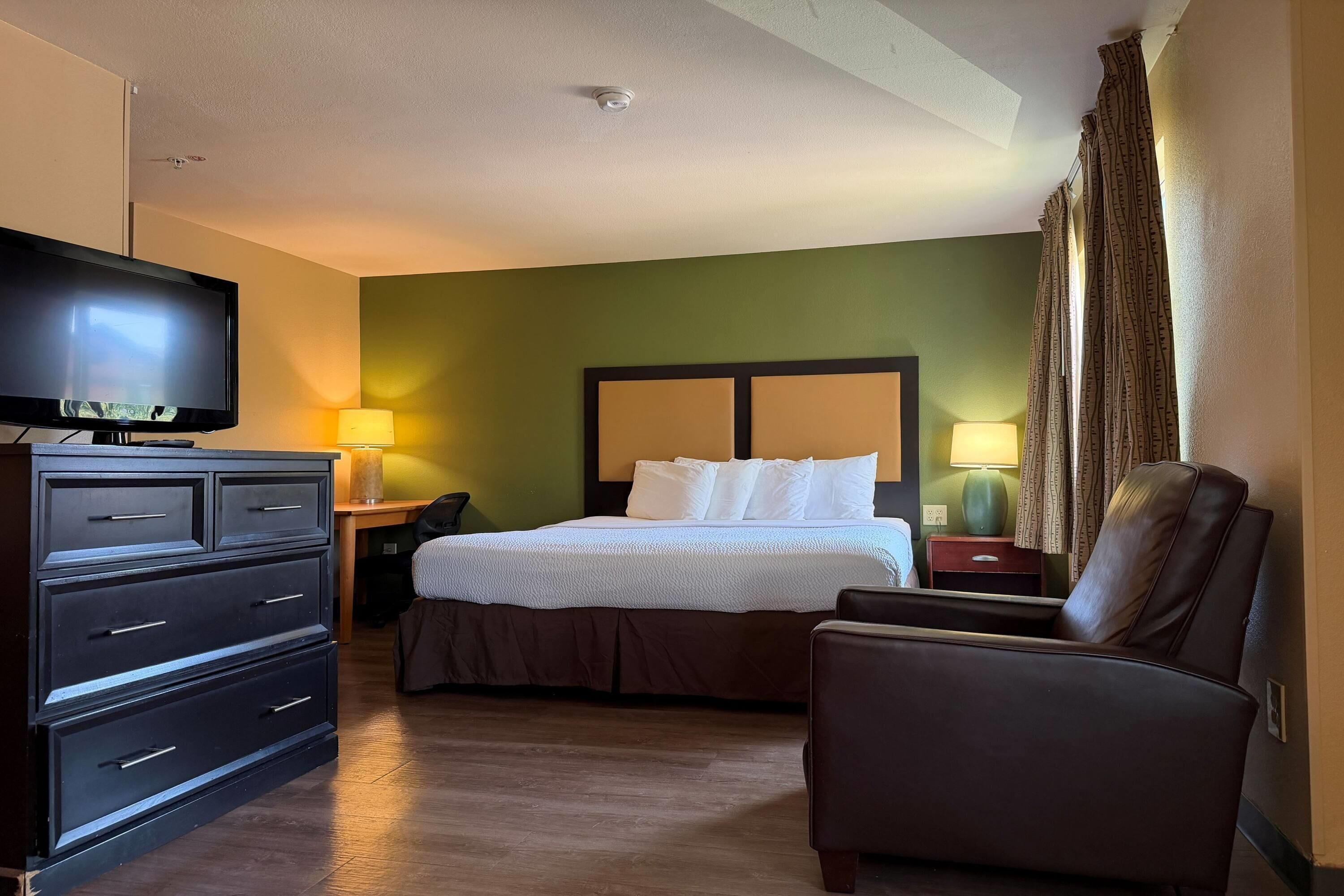 Una habitación de hotel con cama, televisión, escritorio, silla y lámpara.