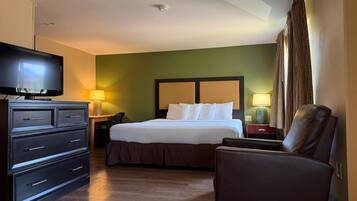 Una habitación de hotel con cama, televisión, escritorio, silla y lámpara.