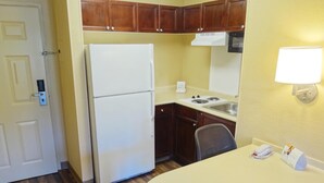 Una cocina compacta equipada con refrigerador, estufa, fregadero y un pequeño comedor.