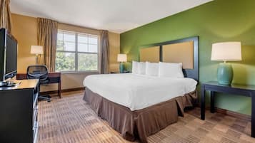 Una habitación de hotel con una cama grande, un escritorio, una silla, dos lámparas y una ventana con cortinas.