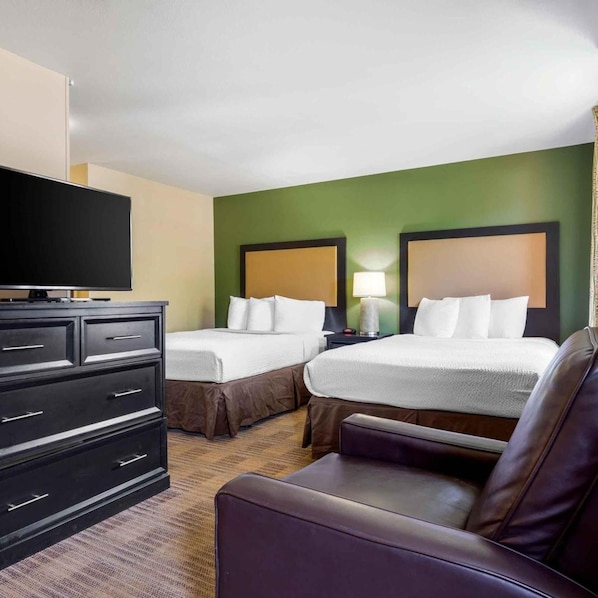 A hotel room with two beds, a TV, a desk, and a chair.