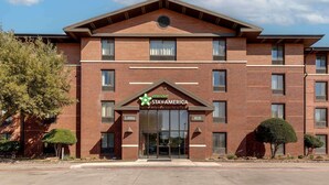 Un edificio de ladrillo con un letrero que dice “extended STAY AMERICA” y la entrada del vestíbulo.
