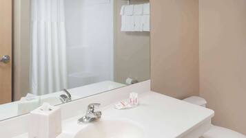 Un baño con lavamanos, espejo y inodoro blancos.