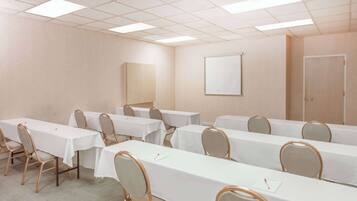 A conference room with multiple tables and chairs, a whiteboard, and a door.