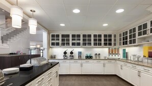 A modern kitchen with white cabinets, a black countertop, and a wooden floor.
