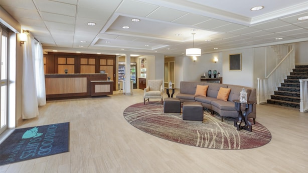 A spacious lobby with a reception desk, a sofa, and a staircase.