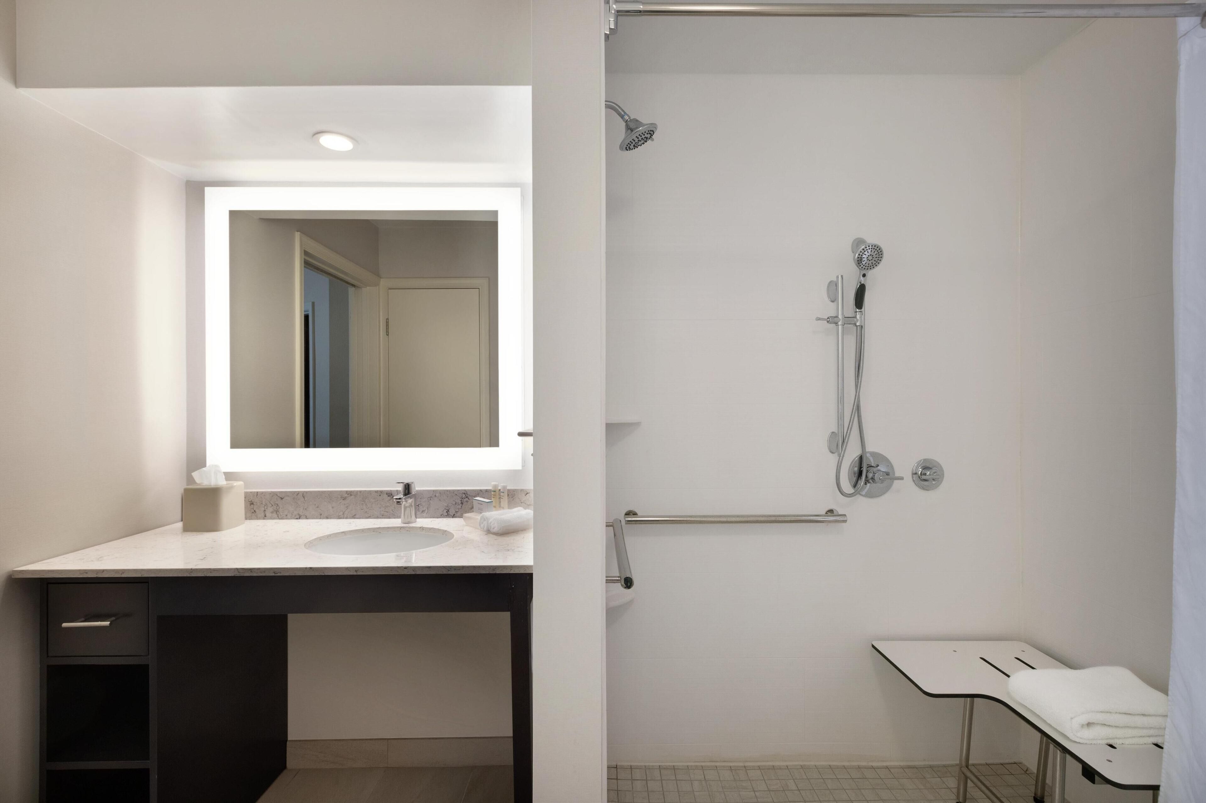 A modern bathroom with a large mirror, a sink, and a shower area.