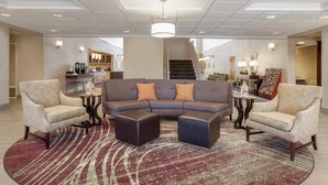A modern living area with a sectional sofa, two armchairs, and a patterned rug.