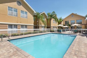 A swimming pool with a white fence, palm trees, and outdoor seating. - Homewood Suites by Hilton St. Petersburg Clearwater (Clearwater)