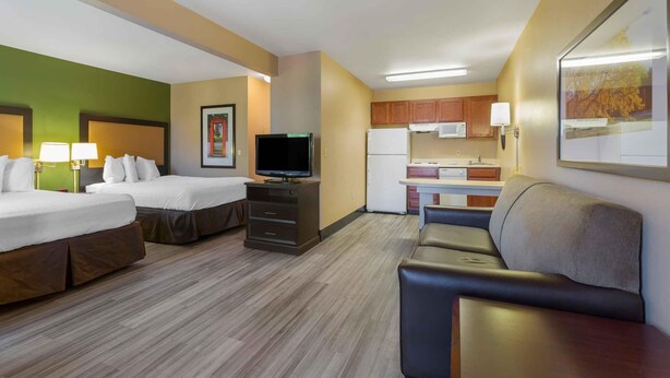 Une chambre d’hôtel avec deux lits, une télévision, une kitchenette et un coin salon.