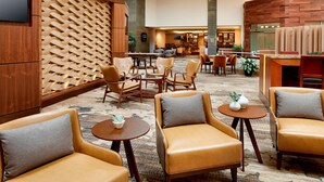 Un hall d’hôtel doté de fauteuils en cuir, d’un bar et d’un espace salon avec un tapis à motifs.