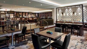 Un hall d’hôtel comprenant un bar, des espaces aménagés pour s’asseoir et un mur décoré de motifs.