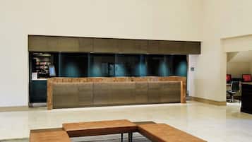 Een ruime lobby met een lange receptiebalie, een moderne kroonluchter en een hoekbank.