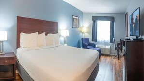 A hotel room with a large bed, a desk, a chair, a television, and a window with curtains. - Baymont by Wyndham Delaware (Delaware)