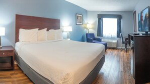 A hotel room with a large bed, a desk, a chair, a TV, and a window with curtains. - Baymont by Wyndham Delaware (Delaware)